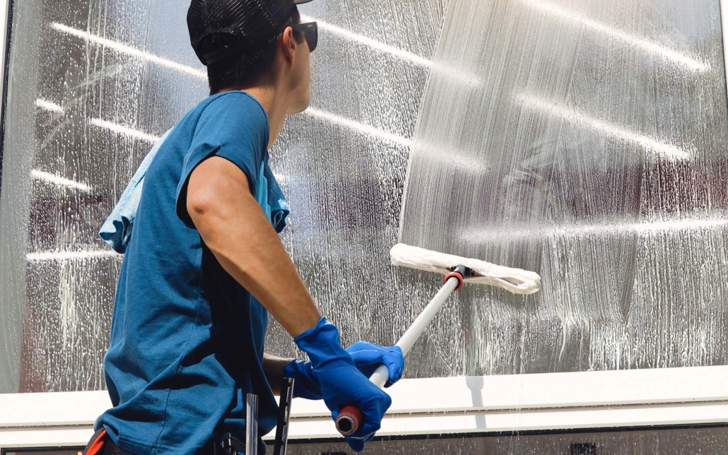 Professional Janitor Wiping Down Window On Commercial Building