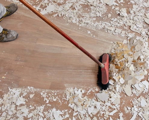 Builder Sweeping The Floor After Renovation